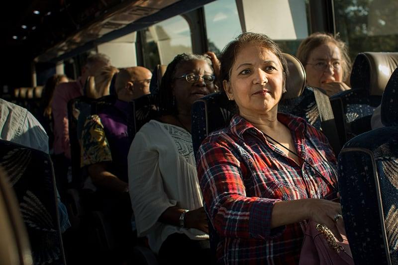 A group of new faculty members sit together on a bus